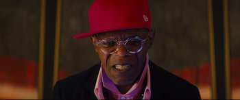 Movie still from “Kingsman: The Secret Service” (2014), directed by Matthew Vaughn – An older man wearing glasses and a red hat; Close Up shot, Over the shoulder angle