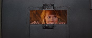 Movie still from “Kingsman: The Secret Service” (2014), directed by Matthew Vaughn – A woman peeking out of a metal door; Medium shot, Over the shoulder angle