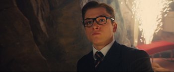 Movie still from “Kingsman: The Secret Service” (2014), directed by Matthew Vaughn – A man in a suit and tie wearing glasses; Close Up shot, Low angle