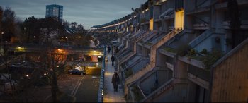 Movie still from “Kingsman: The Secret Service” (2014), directed by Matthew Vaughn – People walking down a sidewalk next to an apartment complex; Extreme Wide shot, High angle