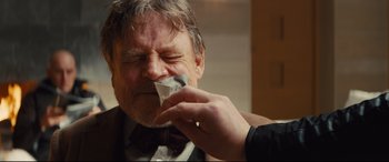 Movie still from “Kingsman: The Secret Service” (2014), directed by Matthew Vaughn – An older man is drinking from a paper cup; Close Up shot, Over the shoulder angle