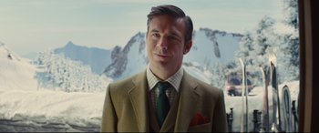 Movie still from “Kingsman: The Secret Service” (2014), directed by Matthew Vaughn – A man wearing a suit and tie standing in front of a snowy mountain; Close Up shot, Over the shoulder angle