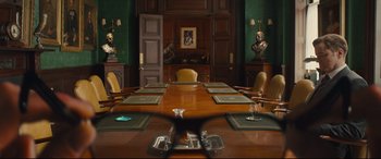 Movie still from “Kingsman: The Secret Service” (2014), directed by Matthew Vaughn – A large wooden table in the middle of a conference room; Extreme Close Up shot, Over the shoulder angle