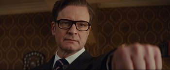Movie still from “Kingsman: The Secret Service” (2014), directed by Matthew Vaughn – A person wearing a suit and glasses; Close Up shot, Low angle