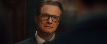 Movie still from “Kingsman: The Secret Service” (2014), directed by Matthew Vaughn – A person wearing glasses and a suit; Close Up shot, Over the shoulder angle