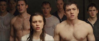 Movie still from “Kingsman: The Secret Service” (2014), directed by Matthew Vaughn – A group of young men and a woman standing next to each other; Medium shot, Low angle