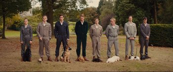 Movie still from “Kingsman: The Secret Service” (2014), directed by Matthew Vaughn – A group of men standing next to each other in a field; Wide shot, Low angle