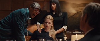 Movie still from “Kingsman: The Secret Service” (2014), directed by Matthew Vaughn – A woman sitting at a table with two other women; Medium shot, Over the shoulder angle