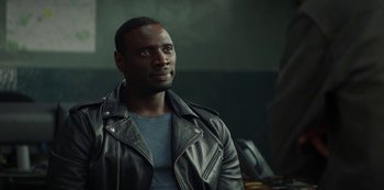 Movie still from “Lupin” (2021), created by Tigran Rosine – A man in a leather jacket looking to his left; Close Up shot, Over the shoulder angle
