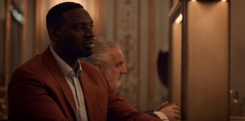 Movie still from “Lupin” (2021), created by Tigran Rosine – A man sitting in front of another man in front of a window; Close Up shot, Over the shoulder angle