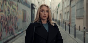 Movie still from “Lupin” (2021), created by Tigran Rosine – A woman with blonde hair wearing a black coat; Close Up shot, Low angle
