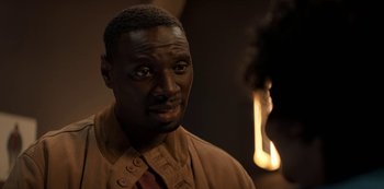 Movie still from “Lupin” (2021), created by Tigran Rosine – A person wearing a suit and tie; Close Up shot, Over the shoulder angle