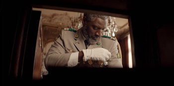 Movie still from “Lupin” (2021), created by Tigran Rosine – A man in a military uniform looking at his watch; Close Up shot, Low angle