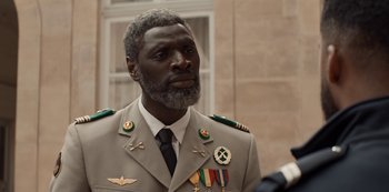 Movie still from “Lupin” (2021), created by Tigran Rosine – A man in a military uniform wearing medals; Close Up shot, Over the shoulder angle