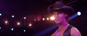 Movie still from “Magic Mike” (2012), directed by Steven Soderbergh – A woman wearing a cowboy hat in front of lights; Close Up shot, Over the shoulder angle