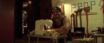 Movie still from “Magic Mike” (2012), directed by Steven Soderbergh – A man sitting in front of a sewing machine; Medium shot, Low angle