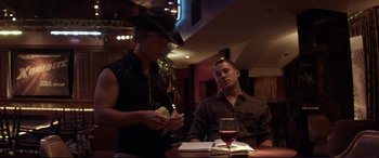 Movie still from “Magic Mike” (2012), directed by Steven Soderbergh – Two men sitting at a table with a glass of red wine; Medium shot, Low angle
