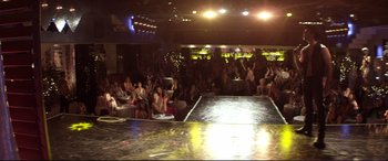 Movie still from “Magic Mike” (2012), directed by Steven Soderbergh – A group of people sitting in front of a runway; Extreme Wide shot, High angle