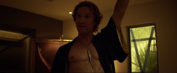 Movie still from “Magic Mike” (2012), directed by Steven Soderbergh – A shirtless man with a long necklace in a dark room; Medium shot, Low angle