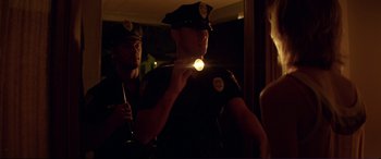Movie still from “Magic Mike” (2012), directed by Steven Soderbergh – A police officer is holding a flashlight in the dark; Medium shot, Low angle
