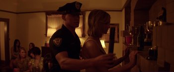 Movie still from “Magic Mike” (2012), directed by Steven Soderbergh – A police officer standing next to a woman in a room; Medium shot, Over the shoulder angle