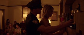 Movie still from “Magic Mike” (2012), directed by Steven Soderbergh – A police officer standing next to a woman in a dark room; Medium shot, Over the shoulder angle