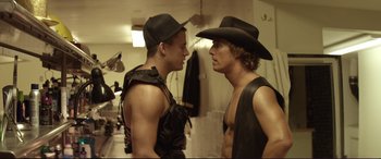 Movie still from “Magic Mike” (2012), directed by Steven Soderbergh – Two men in black hats one of which is wearing a black shirt and the other is wearing a black shirt; Medium shot, Over the shoulder angle