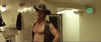 Movie still from “Magic Mike” (2012), directed by Steven Soderbergh – A shirtless man in a cowboy hat in a room; Medium shot, Over the shoulder angle