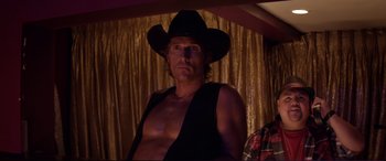 Movie still from “Magic Mike” (2012), directed by Steven Soderbergh – A man in a cowboy hat is posing for a picture; Medium shot, Over the shoulder angle