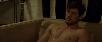 Movie still from “Magic Mike” (2012), directed by Steven Soderbergh – A shirtless man sitting on top of a brown couch; Close Up shot, High angle
