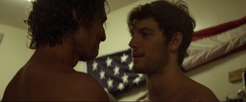 Movie still from “Magic Mike” (2012), directed by Steven Soderbergh – Two young men face each other in front of an american flag; Close Up shot, Over the shoulder angle