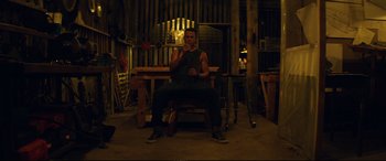 Movie still from “Magic Mike XXL” (2015), directed by Gregory Jacobs – A man sitting on a chair in a room; Wide shot, Low angle