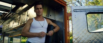 Movie still from “Magic Mike XXL” (2015), directed by Gregory Jacobs – A man in a white tank top is holding a cigarette; Medium shot, Low angle