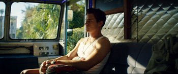 Movie still from “Magic Mike XXL” (2015), directed by Gregory Jacobs – A man sitting in a vehicle with his arm resting on his chest; Medium shot, Over the shoulder angle