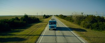 Movie still from “Magic Mike XXL” (2015), directed by Gregory Jacobs – A bus driving down a road near a grassy field; Extreme Wide shot, Low angle