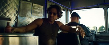 Movie still from “Magic Mike XXL” (2015), directed by Gregory Jacobs – A man sitting on a bus wearing sunglasses; Medium shot, Low angle