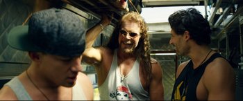 Movie still from “Magic Mike XXL” (2015), directed by Gregory Jacobs – A man with long hair and sunglasses on a bus; Medium shot, Over the shoulder angle
