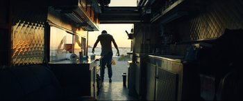 Movie still from “Magic Mike XXL” (2015), directed by Gregory Jacobs – A man standing inside of a kitchen looking out a window; Wide shot, Low angle
