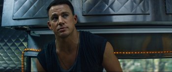 Movie still from “Magic Mike XXL” (2015), directed by Gregory Jacobs – A man in a black shirt is sitting in front of a fire place; Close Up shot, Low angle