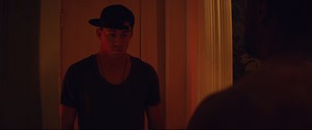 Movie still from “Magic Mike XXL” (2015), directed by Gregory Jacobs – A young man wearing a black hat looking into a mirror; Medium shot, Over the shoulder angle