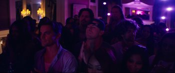 Movie still from “Magic Mike XXL” (2015), directed by Gregory Jacobs – A group of people standing in a room with purple lights; Medium shot, Over the shoulder angle