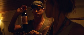 Movie still from “Magic Mike XXL” (2015), directed by Gregory Jacobs – A man holding a bottle of wine in front of a woman; Medium shot, Over the shoulder angle