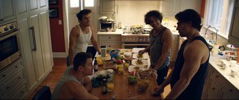 Movie still from “Magic Mike XXL” (2015), directed by Gregory Jacobs – A group of young men standing around a table; Medium shot, High angle