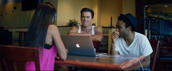 Movie still from “Magic Mike XXL” (2015), directed by Gregory Jacobs – A man sitting at a table with two other people; Medium shot, Over the shoulder angle