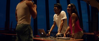Movie still from “Magic Mike XXL” (2015), directed by Gregory Jacobs – A group of people standing around a table with a laptop on it; Medium shot, Low angle