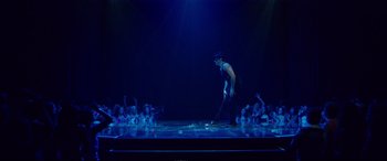 Movie still from “Magic Mike XXL” (2015), directed by Gregory Jacobs – A man standing on a stage in front of a group of people; Wide shot, Over the shoulder angle