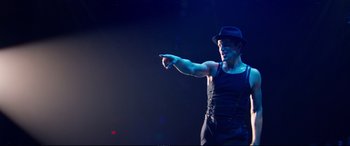 Movie still from “Magic Mike XXL” (2015), directed by Gregory Jacobs – A man wearing a hat and pointing to the side; Medium shot, Over the shoulder angle