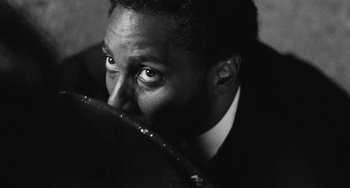 Movie still from “Malcolm & Marie” (2021), directed by Sam Levinson – A black - and - white photo of a man in a suit and tie; Extreme Close Up shot, Low angle