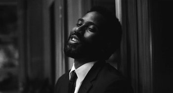 Movie still from “Malcolm & Marie” (2021), directed by Sam Levinson – A black and white photo of a man in a suit and tie; Close Up shot, Overhead angle