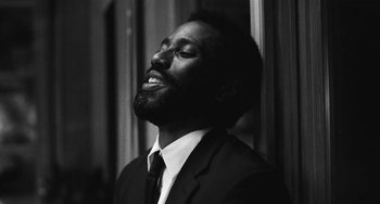 Movie still from “Malcolm & Marie” (2021), directed by Sam Levinson – A black and white photo of a man in a suit and tie; Close Up shot, Low angle